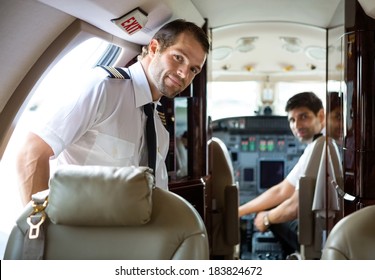 Portrait of handsome pilot entering private jet with copilot in background - Powered by Shutterstock