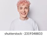 Portrait of handsome pink haired man dressed in casual clothes smiles gladfully concentrated into camera expresses positive emotions isolated over white background. People and face expressions concept