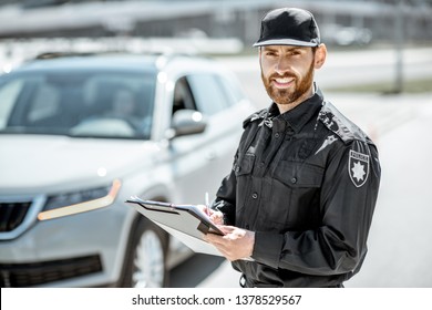 Portrait Of A Handsome Policeman In Uniform Standing In Front Of A Car On The Roadside