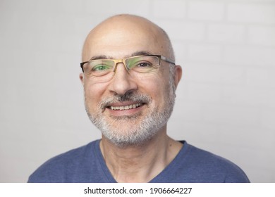 Portrait Of A Handsome Positive 50 Years Old Man With Glasses, Unshaven Hair In A Blue T-shirt Indoors.