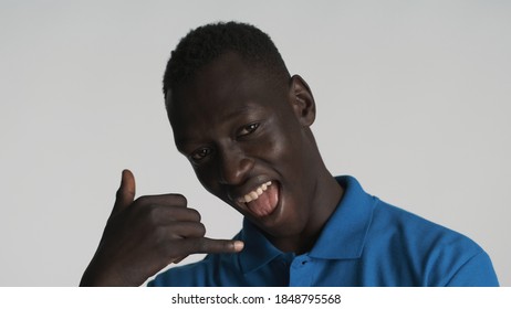 Portrait Of Handsome Positive African American Guy Keep Hands Near Face Showing Call Me Gesture On Camera Over White Background