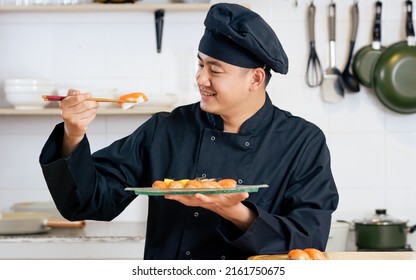 Portrait Handsome Professional Japanese Male Chef Wearing Black Uniform, Hat, Cooking, Showing Sushi Street Food, Smiling With Confidence, Happiness, Standing In Kitchen. Restaurant, Hotel Concept