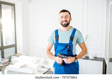 Portrait Of A Handsome Repairman In Workwear Standing With Screwdriver In The Office