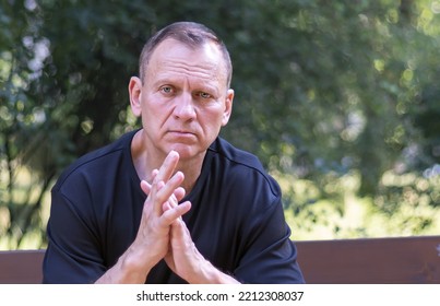 Portrait Of A Handsome Sad Man, 55-60 Years Old, In The Park, Sitting On A Bench