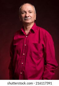 Portrait Of Handsome Senior Man Looking At The Camera On Dark Red Background