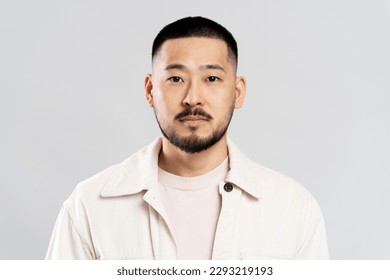 Portrait of handsome serious asian man with stylish hair, wearing casual clothes, looking at camera after barbershop service, isolated on white background - Shutterstock ID 2293219193