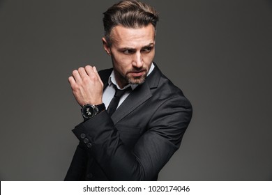 Portrait Of Handsome Serious Businessman In Black Suit Looking Aside With Fancy Wrist Watch Isolated Over White Background