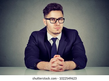 Portrait of handsome serious businessman sitting at table in office looking at camera. 