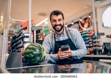 Portrait Of Handsome Smiling Male Cashier Working At A Grocery Store.