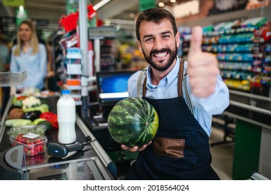 Portrait Of Handsome Smiling Male Cashier Working At A Grocery Store.