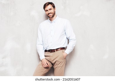 Portrait Of Handsome Smiling Model. Sexy Stylish Man Dressed In Shirt And Trousers. Fashion Hipster Male Posing Near Grey Wall In Studio