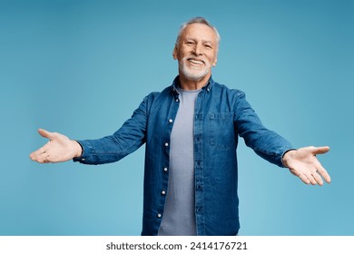 Portrait of handsome smiling senior gray haired man wearing stylish casual denim shirt, looking at camera with open arms standing isolated on blue background. Positive lifestyle concept - Powered by Shutterstock