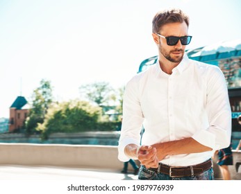 Portrait of handsome smiling stylish hipster lambersexual model.Modern man dressed in white shirt. Fashion male posing on the street background in sunglasses. Outdoors at sunset  - Powered by Shutterstock