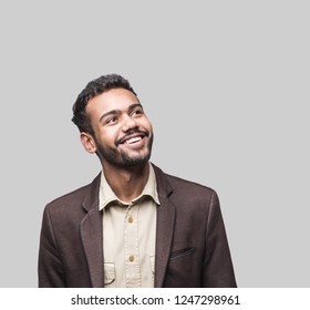 Portrait Of Handsome Smiling Young Man Looking Up. Laughing Joyful Cheerful Men Studio Shot. Isolated On Gray Background