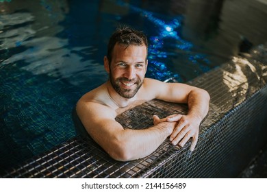 Portrait Of Handsome Smiling Young Man Relaxing By The Swimming Pool Edge