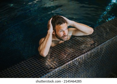 Portrait Of Handsome Smiling Young Man Relaxing By The Swimming Pool Edge