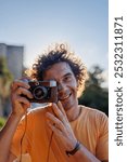 Portrait of a handsome stylish young man with a camera in his hands. A man looks through the lens of an old-fashioned camera and takes a photo. film camera.