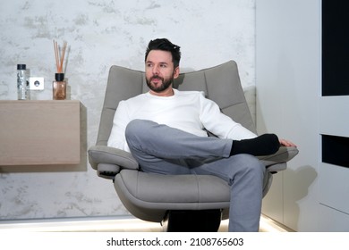 Portrait Of Handsome Successful Rich Relaxed Man, Young Person Is Sitting In Comfortable Armchair At His Luxury Flat, Apartment Or Home, Relaxing, Resting, Having A Rest, Dreaming, Thinking. 