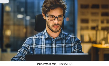 Portrait of the Handsome and Successful Young Creative Entrepreneur Working at His Desk Using Laptop Computer. Working from Cozy Home Office, Studio with Window View of the City at Night - Shutterstock ID 1804298134