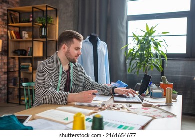 Portrait of handsome tailor working in atelier studio sewing suit jacket at table - Shutterstock ID 2161654677