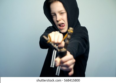 Portrait Of A Handsome Teenage Bad Boy With Slingshot And Stylish Haircut, Softbox Lighting Studio Shot.