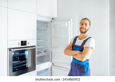 Portrait Of A Handsome Workman Installing New Refrigerator In The Modern Kitchen At Home