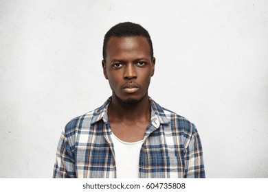 Portrait Of Handsome Young African American Male Dressed In Blue Checkered Shirt Over White T-shirt Looking At Camera With Serious And Confident Expression On His Face. People And Lifestyle Concept