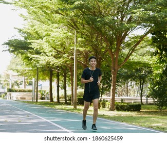 Portrait Of A Handsome Young Asian Guy Sportsman Jogging Listening To Training Music On Smartphone Concept Love Sports Healthy Lifestyle Running Outside