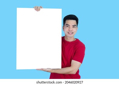 Portrait Handsome Young Asian Man Wearing A Red Shirt Holding A Blank Paper Or Billboard Feeling Happy Isolated On Blue Background. Businessman Concept. 