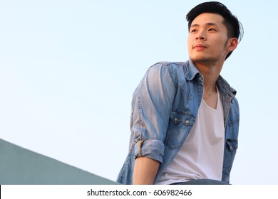 Portrait handsome young asian man  He looking to beautiful sunset, it make him happy. Attractive men feel relax, determined. Cool guy wear denim jacket, jeans. He look confident, determined copy space