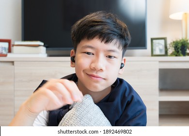 Portrait of a handsome young asian teenager boy's face with earbuds from video chat web cam, he talking to distance friend through online application during Covid-19 pandemic lockdown. New normal. 