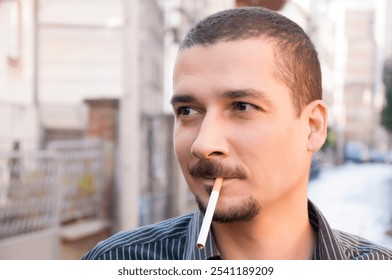 Portrait of handsome young bearded man in the city street smoking a cigarette - Powered by Shutterstock