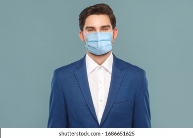 Portrait of handsome young businessman with surgical medical mask looking at camera. Business people medicine and health care concept. Indoor, studio shot on blue background - Powered by Shutterstock