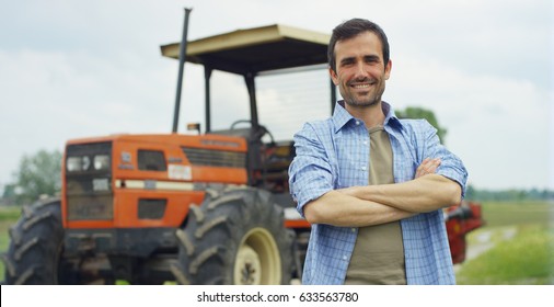 Portrait of a handsome young farmer standing in a shirt and smiling at the camera, on a tractor and nature background. Concept: bio ecology, clean environment, beautiful and healthy people, farmers.
				