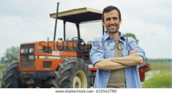 Portrait of a handsome young farmer standing\
in a shirt and smiling at the camera, on a tractor and nature\
background. Concept: bio ecology, clean environment, beautiful and\
healthy people,\
farmers.\
