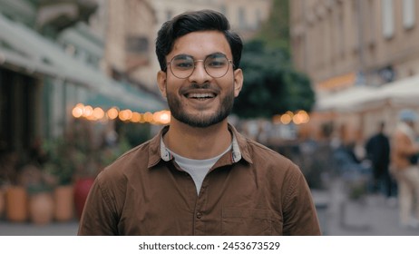 Portrait handsome young gen z Indian Arabian ethnic man guy male happy successful businessman model smiling student client looking camera cheerful smile business outside evening city street cafeteria - Powered by Shutterstock