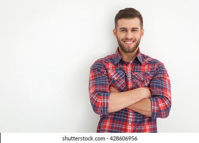 Portrait Of Handsome Young Guy Standing Against White Wall.