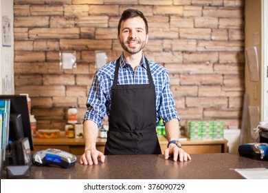 Portrait Of A Handsome Young Hispanic Business Owner Standing At The Checkout Counter And Smiling