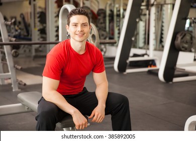 Portrait Of A Handsome Young Hispanic Man Sitting On A Bench At The Gym And Smiling