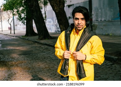 A portrait of a handsome young latino man walking alone down a street on a sunny day