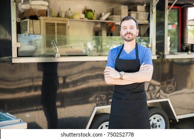 Portrait of a handsome young man with an apron standing in front of his food truck - Powered by Shutterstock