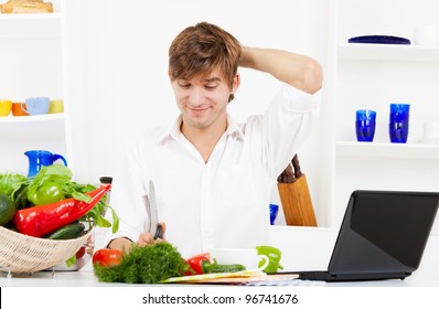 Portrait Of Handsome Young Man Cooking In The Kitchen, Problem Prepare Vegetable Salad Fail, Hold Hand On Head, Laptop Screen With Receipt