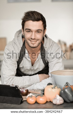 Portrait of a handsome young man cooking with digital tablet in kitchen