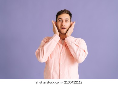 Portrait Of Handsome Young Man Covering Ears With Hands Do Not Wanna Listen Standing On Pink Isolated Background In Studio Looking At Camera. Concept Of Silence.