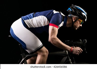 Portrait of handsome young man cycling indoor. Isolated on black.