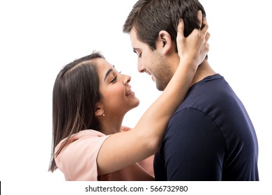 Portrait of a handsome young man getting pulled into a kiss by his girlfriend in a studio