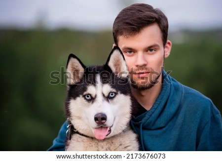 Portrait of handsome young man and his pet dog Siberian Husky in nature.