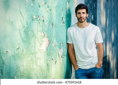 Portrait Of A Handsome Young Man In Jeans And White T-shirt Leaning To The Old Wall.