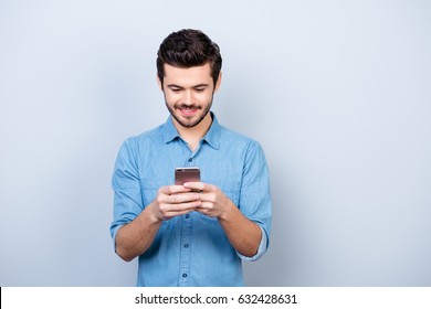 Portrait of handsome young man looking at his phone and smiling, he got message from his girlfriend