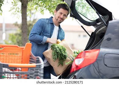 Portrait Of Handsome Young Man Packing Groceries Into Car Trunk